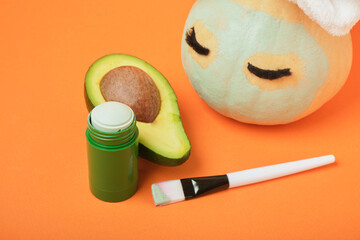 Avocado mask stick concept, pumpkin and avocado on an orange background, autumn beauty care