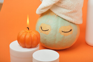 Mock-up jars of cream and yellow pumpkin in a clay mask and a towel on the head Natural organic spa cosmetics concept. Vitamin intense seed of pumpkin cream concept.