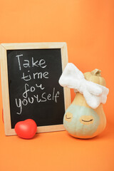 A cute pumpkin from a spa salon and a chalkboard with the inscription "take time for yourself" on an orange background