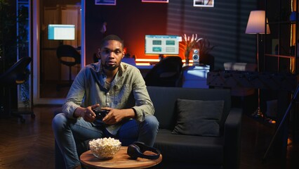 POV young black adult enjoying free time playing shooter games on smart tv, plugging console in the living room and spending game session at night. Man engaging in fun activity. Camera A.