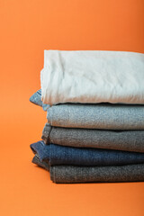 a stack of jeans of different colors on an orange background