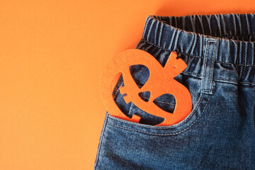 Blue jeans and a felt pumpkin on an orange background