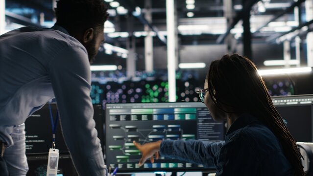 Data center manager supervising engineer using node tree tool to identify equipment performance issues. Server hub team leader talks with IT specialist reviewing data analysis graph, camera B - Powered by Adobe