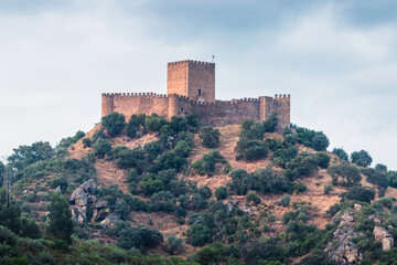 Fototapeta premium Belver Castle on top of a hill at sunset, with a serene sky and soft clouds in Portugal.