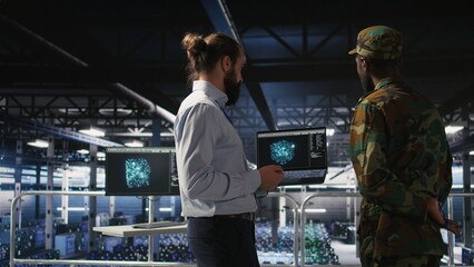 Military operator and IT expert in army data center using AI on laptop to manage autonomous defense systems. Soldier and programmer using AI for strategic threat detection,