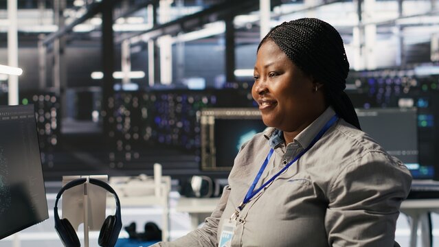 Data center programmer coding on PC, doing software updates for AI visualization systems. African american woman in server room optimizing infrastructure using artificial intelligence, camera A - Powered by Adobe