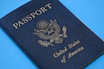 United States passport book on light blue paper background close up. Travel document on blue surface