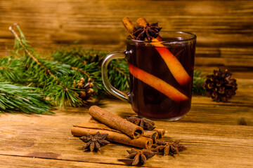 Cup of mulled wine with cinnamon and fir tree branches on wooden table