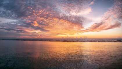 Morning sky with glowing altocumulus clouds over a calm ocean at sunrise
