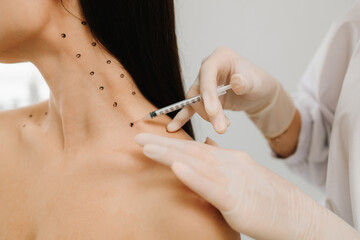 Nefertiti lifting injection in marked dotes on the neck. Cosmetologist is drawing dotes before...