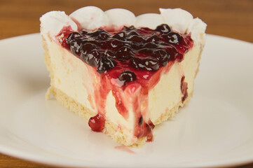 Cheesecake with elderberry jelly topping on a white background, close-up shot with copy space