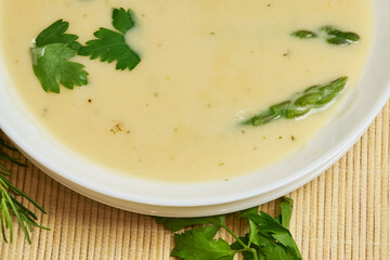 A bowl of asparagus soup in the foreground with rustic decor and background, high studio shots with copy space