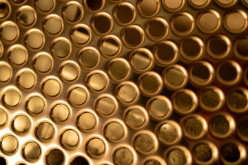 Golden metal surface background with repeating round perforations