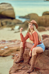 Young cowgirl posing outdoors in western fashion at sunset