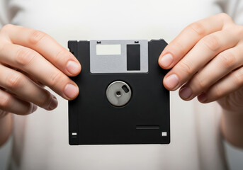Hands holding a classic 3.5 inch floppy disk, an iconic and nostalgic symbol of past technology and obsolete data storage