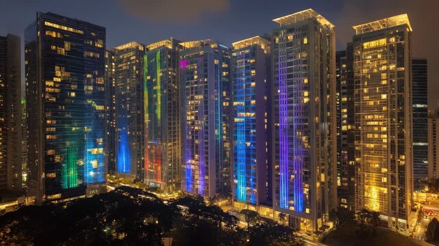 Vibrant laser ads beam onto highrise buildings in a bustling cityscape turning architectural surfaces into glowing canvases of creative commercial messaging.