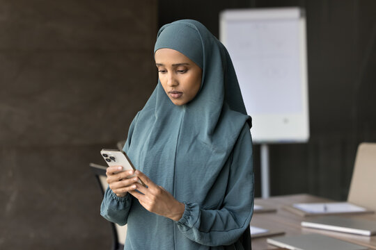 Focused young middle eastern businesswoman read email from cellphone screen