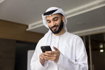 Smiling young middle eastern businessman hold smartphone read message text