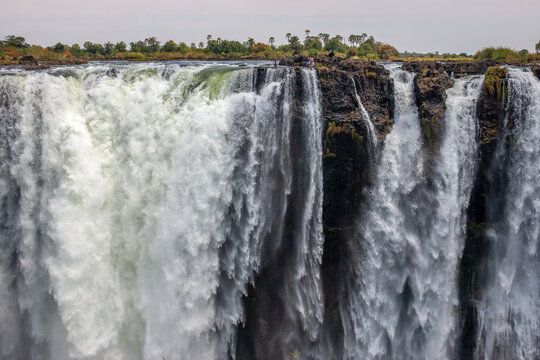People sitting in the Devil's Pool at the edge of the Victoria Falls, Zimbabwe, Africa
