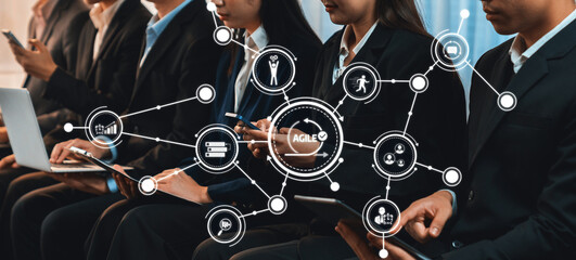 A group of business professionals collaborate using various devices, highlighting the importance of technology and agile methods in a modern corporate setting to enhance teamwork. Amity