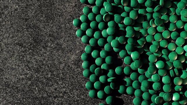 spirulina green algae tablets pouring out on a gray background.Algae food supplement.Natural plant protein and source of iodine. 4k footage