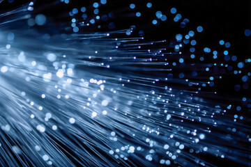 Abstract visual representation of glowing fiber optic cables emitting vibrant blue light dots on a dark background with dynamic depth and motion effects