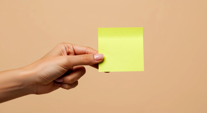 Grab attention with this vibrant yellow sticky note held by a manicured hand for your modern business needs