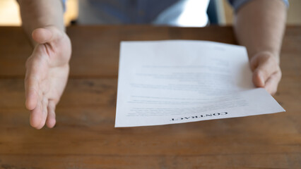 Closeup lawyer holding contract presenting document with open palm gesture