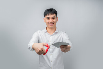 A handsome Asian businessman expresses satisfaction while cutting credit card with red scissors. This concept is suitable for themes of financial freedom, debt reduction, business, and advertising.


