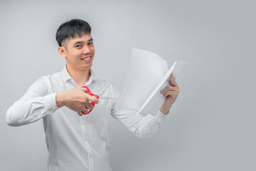 A handsome Asian businessman expresses satisfaction while cutting a financial document with red scissors. This concept is suitable for business, finance, advertising, and debt-free concepts.

