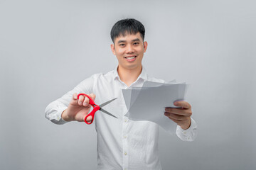 A handsome Asian businessman expresses satisfaction while cutting a financial document with red scissors. This concept is suitable for business, finance, advertising, and debt-free concepts.

