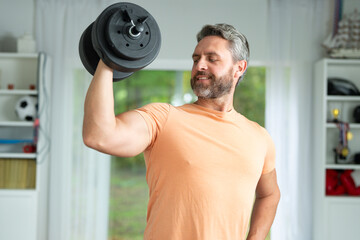 Latin man lifting weights to train biceps at home workout. Sportsman exercising for strong biceps...
