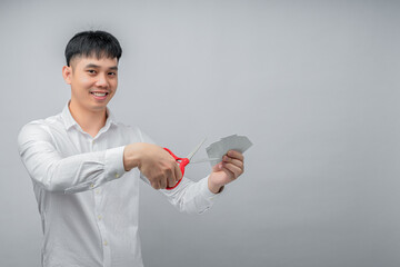 A handsome Asian businessman expresses satisfaction while cutting credit card with red scissors. This concept is suitable for themes of financial freedom, debt reduction, business, and advertising.