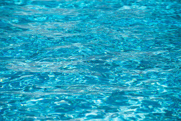 Blue pool water background. Blurred transparent clear calm water surface texture. Water waves in sunlight with copy space.