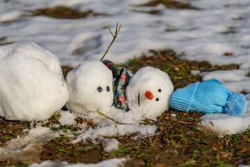 End of winter, hello spring. Melting snowman. Warming season effects. Winter and spring seasons change. Melting snowman with puddles around it. From winter to spring. Melting snowman in warm weather.