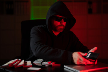 Thief stolen money after a robbery. A masked thief steals money from an office in dark night...
