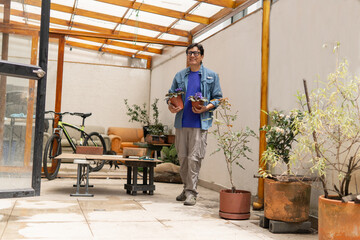 Fototapeta premium Senior man holding potted plants walking in greenhouse