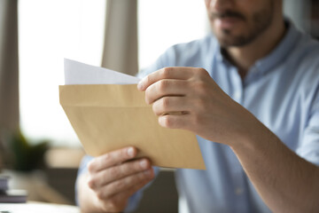 Closeup paper letter in postal envelop in young male hands