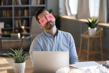 Businessman sleeping at workplace with sticky notes wide open eyes