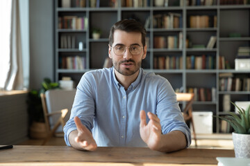 Screen view young male sitting at desk speaking via videocall