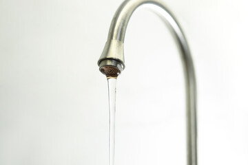 Water saving concept. Stream of water flowing from tap on light background, closeup