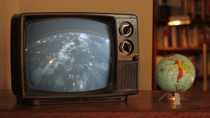 Vintage Television Showing Earth Rotating From Space With Spinning Globe Beside, Warm Interior Light - Elements of this video furnished by NASA - Powered by Adobe