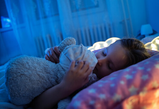 Cute little girl sleeping tight hugging her teddy bear, closeup shot