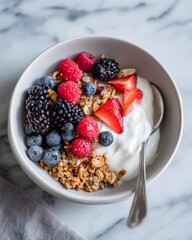 Yogurt bowl topped with berries and granola on marble surface, editorial food composition highlighting healthy breakfast, nutrition, and the modern charm of balanced wellness culture