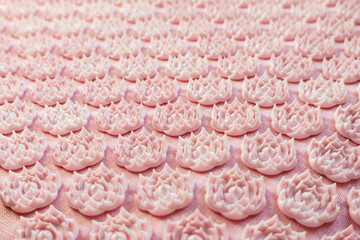 Pink acupuncture mat with lotus-shaped needles close up. Concept of wellness, reflexology and self-care treatments at home. Selective soft focus, copy space