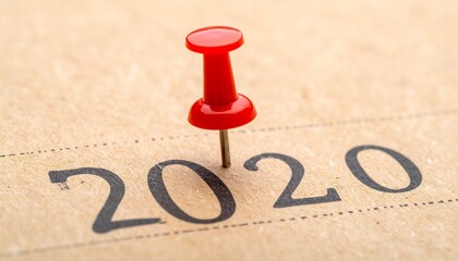 A red pushpin marking the year 2020 on a piece of paper, symbolizing a significant date or event