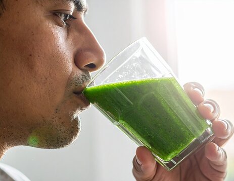 Man drinking a healthy green smoothie made from fresh fruits and vegetables