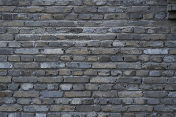A close - up of a brick wall made up of gray bricks, showing a textured and weathered appearance.