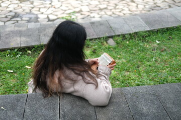 Portrait of Asian woman in sweater playing kalimba music box at city park