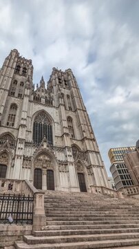 Hyperlapse of the Brussels Cathedral of St. Michael and St. Gudula, Belgium. Gothic spires, intricate carvings and towering facade under a cloudy sky showcase its architectural heritage timelapse